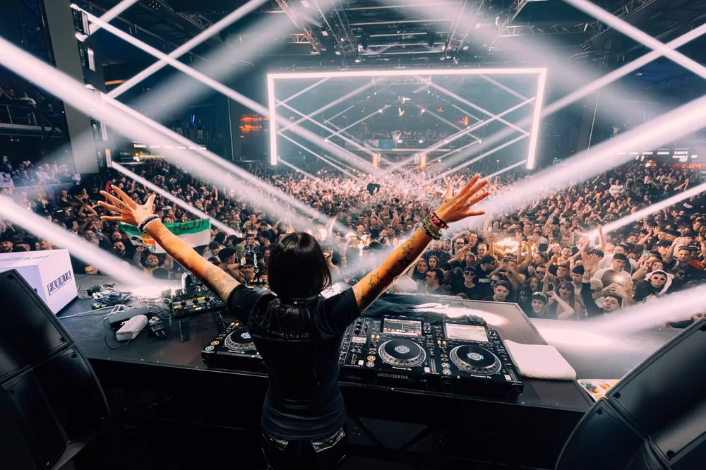 Fátima with her arms open towards the crowd, beneath crossing beams of white light