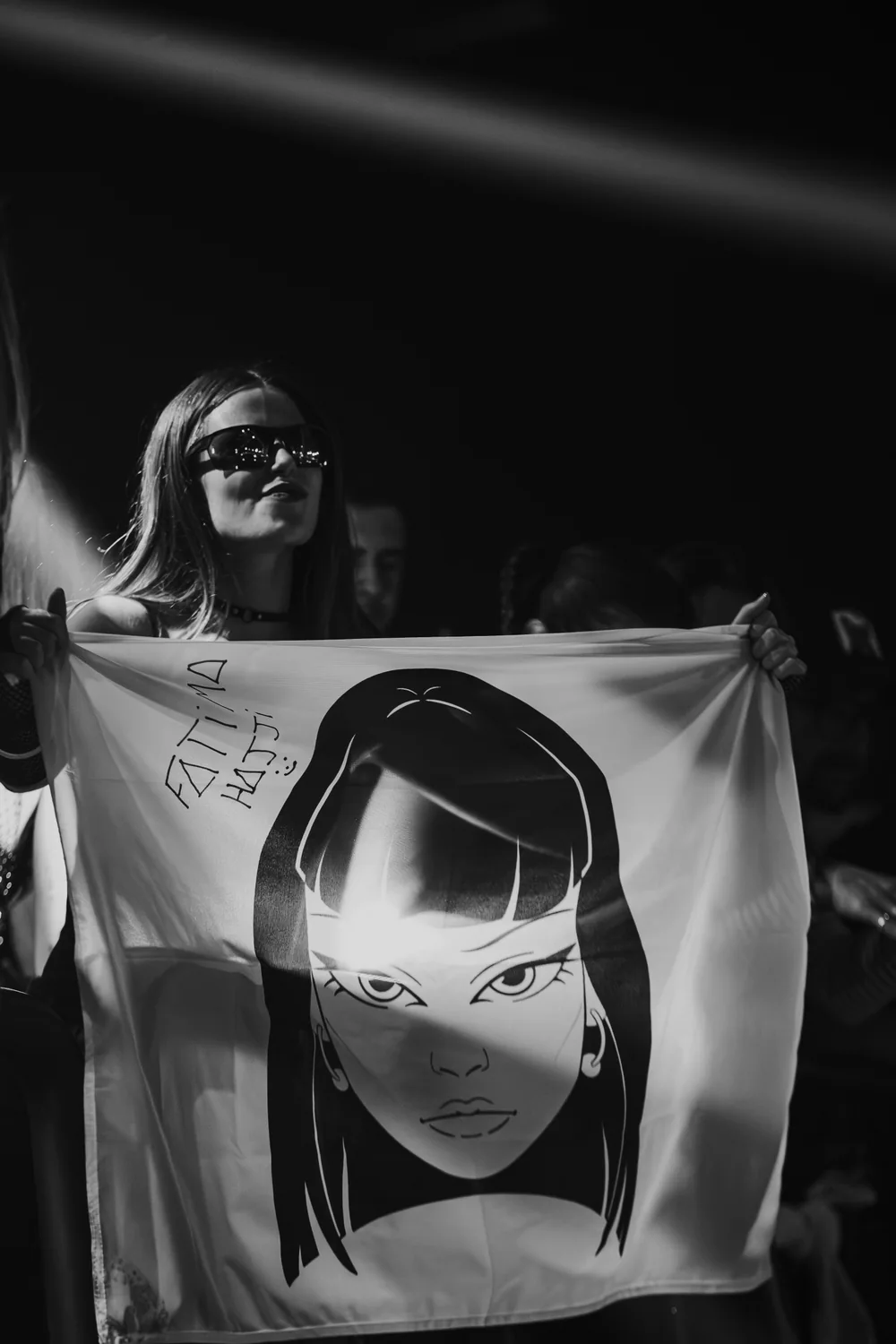 Black and white photograph of Fátima holding a flag with Hajjita’s face